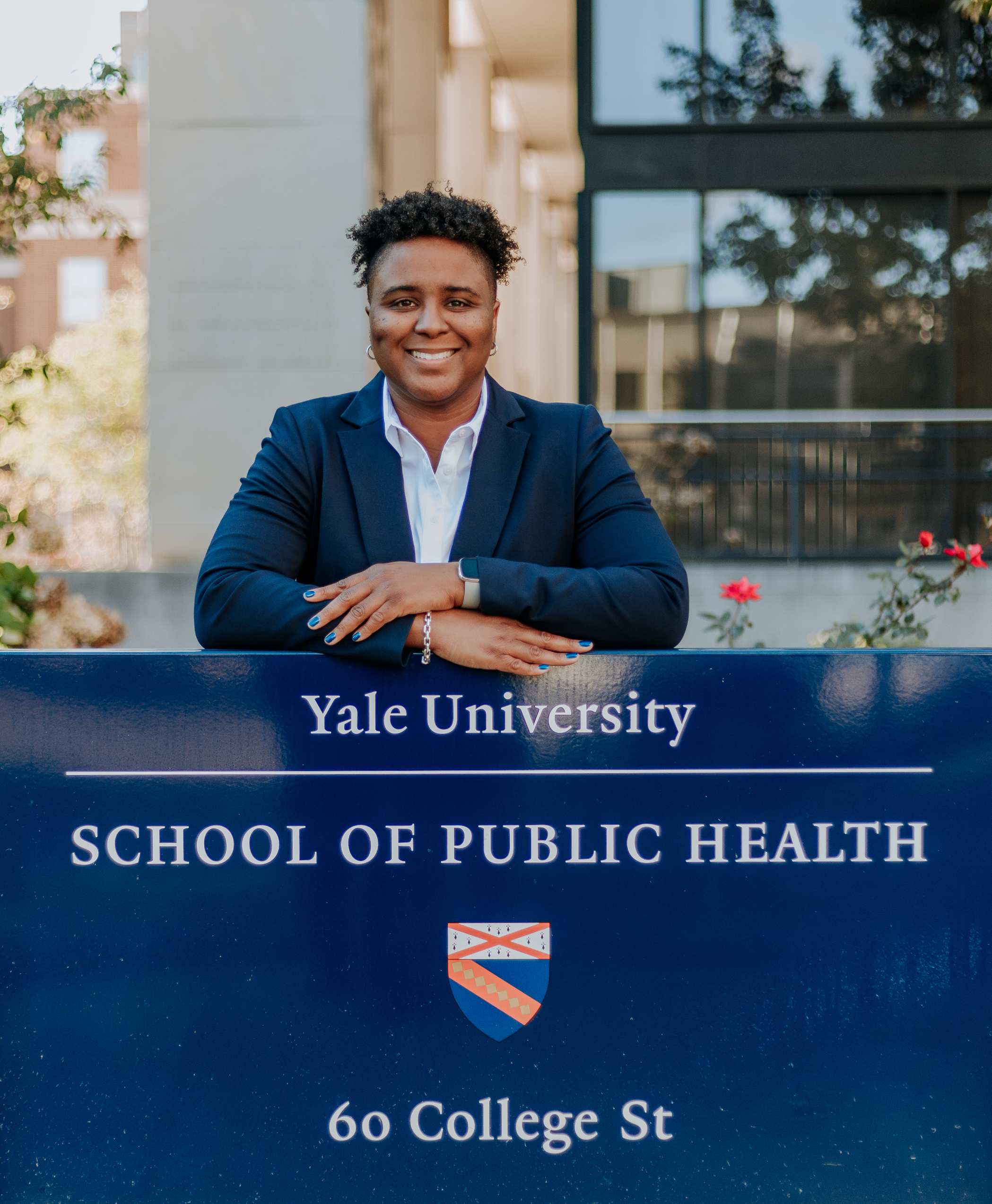 Dr. Terika McCall leaning on the Yale University School of Public Health sign
